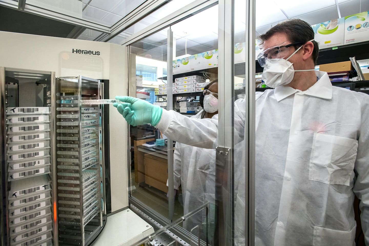 Vedeckí pracovníci v ochranných odevoch pracujúci s laboratórnymi vzorkami.